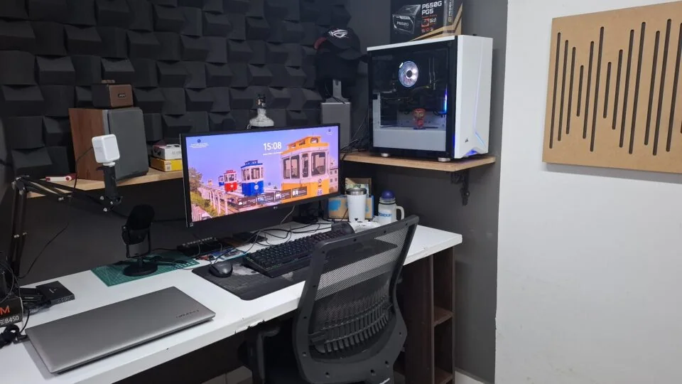 Mesa de trabalho e escritório de produção de conteúdo do portal Inacreditável Mundo Curioso. Computador ligado, teclado, microfone e ambiente de pesquisa de mistérios e histórias.